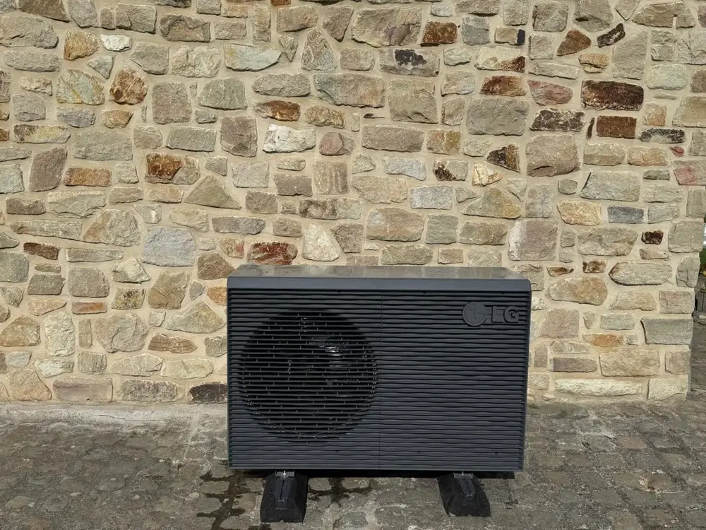 Pompe à chaleur air-eau LG anthracite posée par M2B contre un mur en pierre